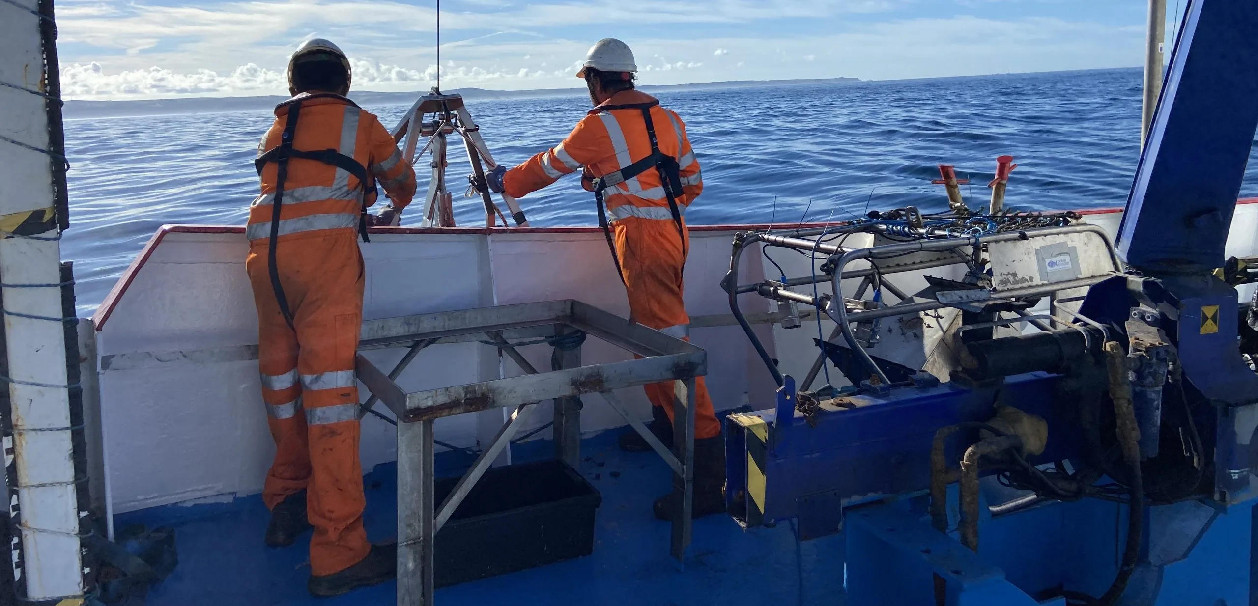 Picture of two of the survey crew preparing to launch a grab off the side of a boat