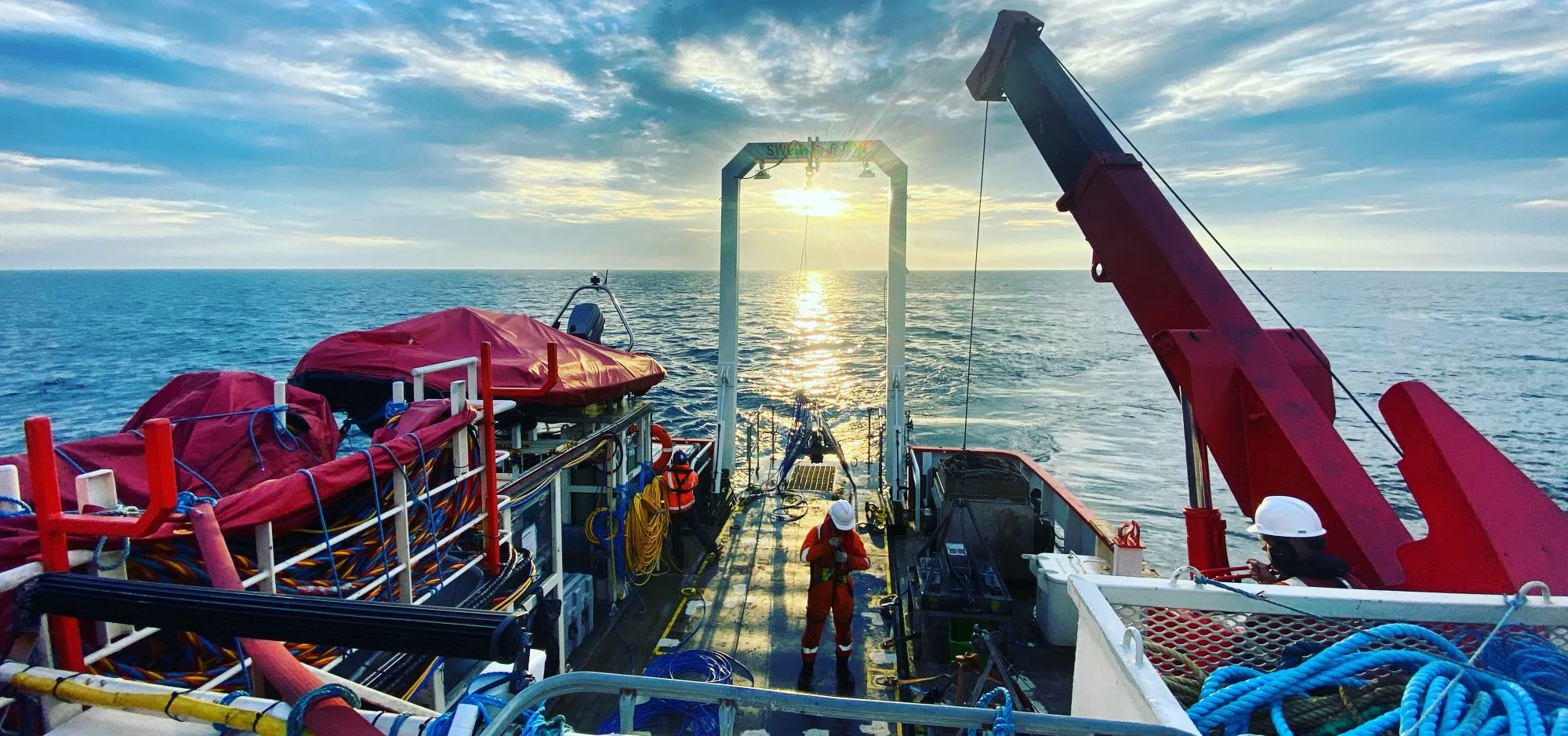 Picture of a survey crew member working on the boat at sunrise